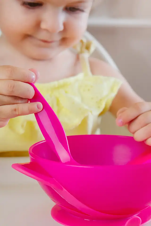 As part of her occupational therapy session, a young girl handles a spoon and bowl to learn about feeding skills.